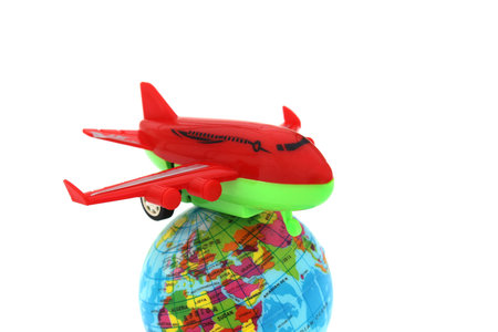 On a white background lies a model of the earth and a toy plane on it.の写真素材