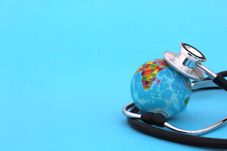 On a blue background lies a mock-up of the earth with a stethoscope with space for text.の写真素材