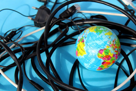 A small globe lies on a blue background, surrounded by wires.