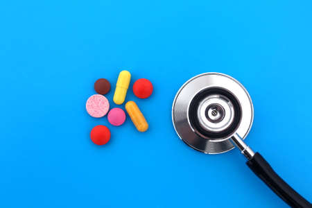 The stethoscope lies on a blue background with pills.の写真素材