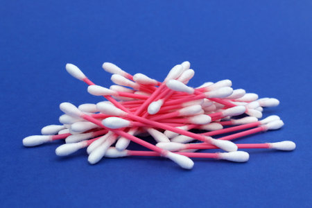 A pile of cotton buds lies on a blue background.の写真素材