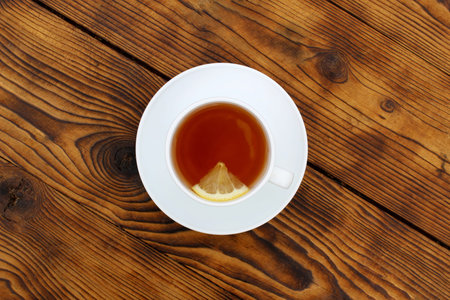 A cup with tea and lemon stands on a wooden table.の写真素材