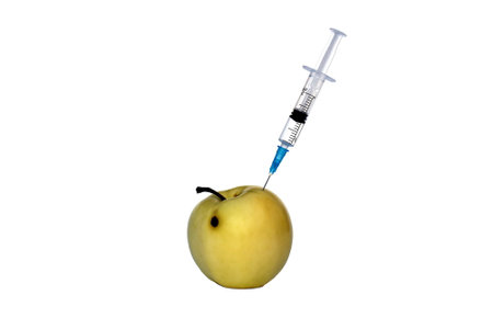 Apple pricked with a syringe on a white isolated background.の写真素材