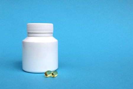 On a blue background, a white package with vitamin D in a capsule.の写真素材