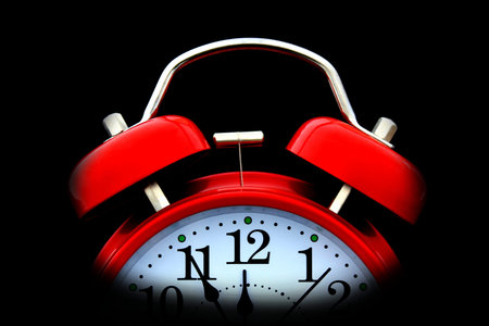 Red alarm clock on a black background.