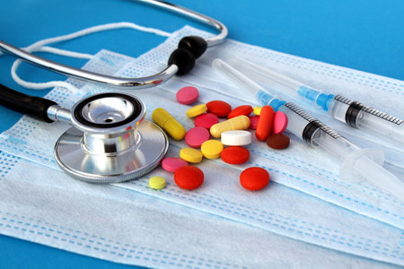 Pills and syringes for a stethoscope lie on medical masks.の写真素材