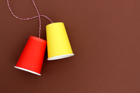 An impromptu phone made of paper bright glasses with a rope on a brown background.の写真素材