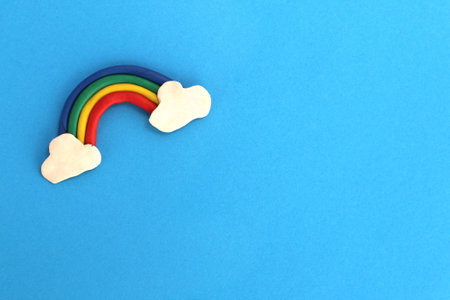 A rainbow molded from plasticine lies on a blue background.の写真素材