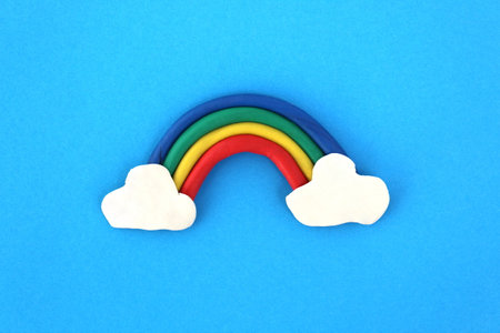 A rainbow molded from plasticine lies on a blue background.の写真素材