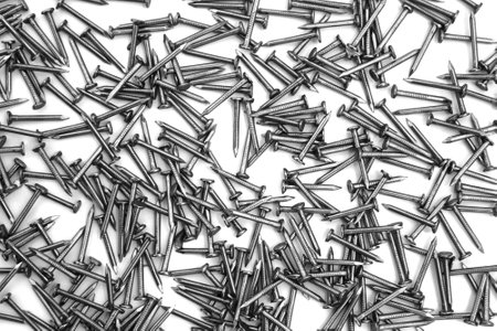 A pile of large iron nails lie on a white backgroundの写真素材