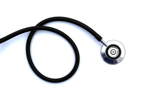 On a white isolated background lies a black stethoscope.の写真素材