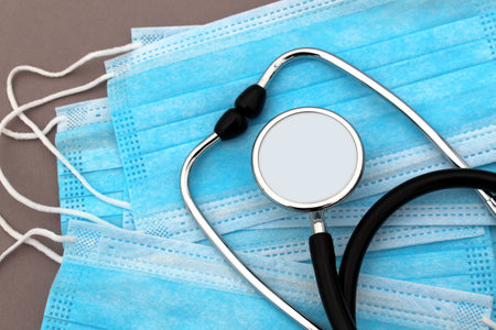 on medical masks lies an iron black stethoscope.の写真素材