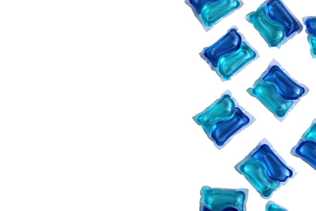 A lot of blue laundry capsules lie on a white background.の写真素材