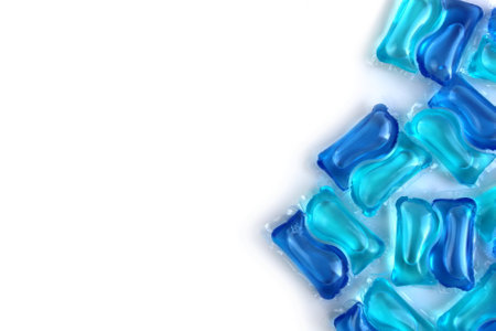 A lot of blue laundry capsules lie on a white background.の写真素材