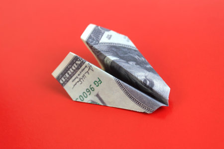 On a bright background lies a homemade plane made from dollar billsの写真素材