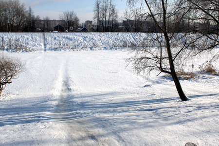 Winter landscape on a sunny day. On the bank of the river, people rolled up a hill.の写真素材