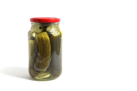 A glass jar with pickles stands on a white background.の写真素材
