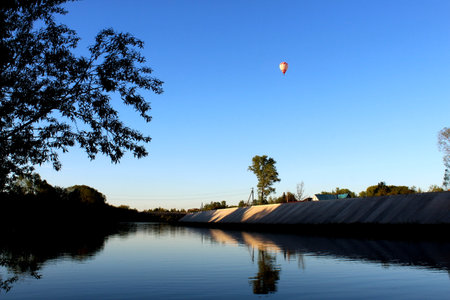A hot air balloon with a basket flies in the evening sky.の写真素材