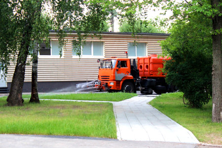 The car drives and waters the sidewalk in hot weather.