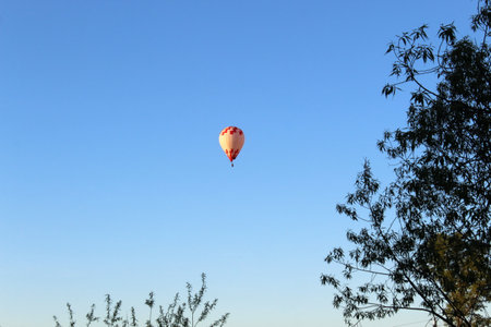 A hot air balloon with a basket flies in the evening sky.の写真素材