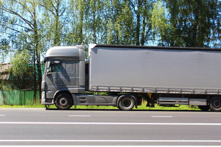 There is a long van parked on the side of the road in summer.の写真素材