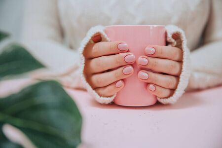 Pink Cup in the hands of a girl on a pink background.の写真素材