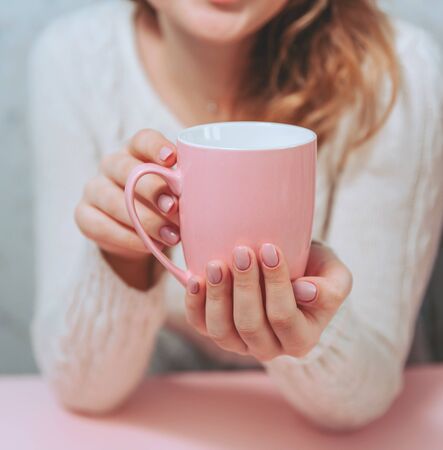 Pink Cup in the hands of a girl on a pink background.の写真素材