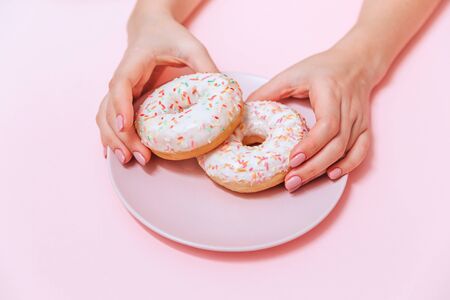 Two delicious, attractive, tempting doughnuts on a pink plate on a pink table.の写真素材