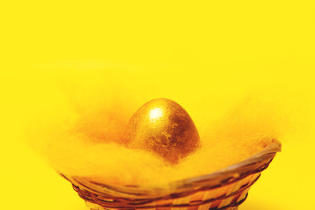 One Golden Easter egg in a basket on a yellow background.