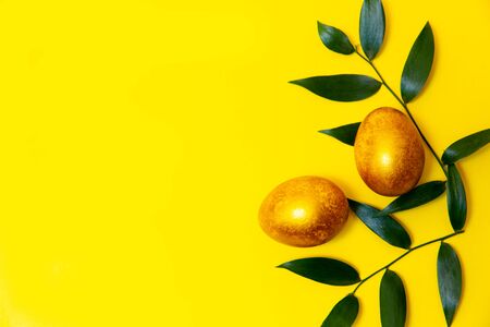 Two Golden Easter eggs on a yellow background.の写真素材