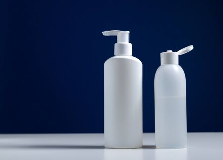 Plastic white antiseptic bottle with a dispenser on a blue background. The white package is on a white table.の写真素材