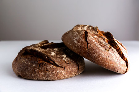 Two round loaves of rye bread on the table. One loaf is on top of the other. Front view.