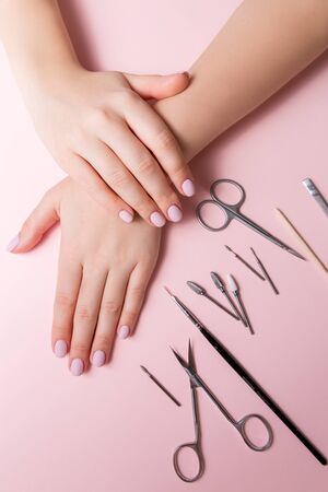 The young girl's hands are well-groomed, her nails are manicured. Manicure tools are spread out on the table. The girl did her own manicure during the quarantine, when it was impossible to leave the house.の写真素材