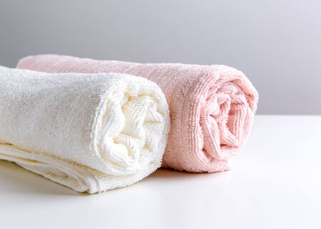 White and coral towels are on the white table. Front view.の写真素材