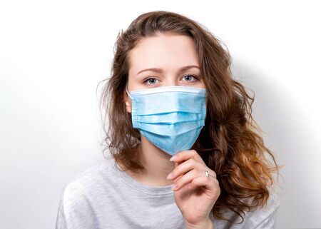 A young woman puts on a medical face mask. Isolate. Medical banner. Relevant for all areas of medical topics.の写真素材