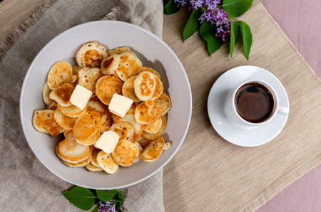 Tiny pancake cereal mini-cakes with butter and coffee in the early spring morning.