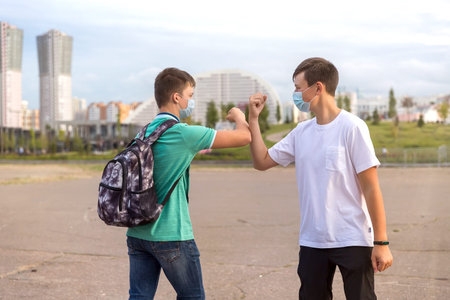 Two friends of teenagers meet in the city. They greet each other without contact .