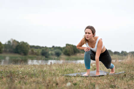 Young sporty woman doing fitness exercises near the river against the background of the forest. Young sporty woman doing fitness exercises near the river against the background of the forest.の写真素材