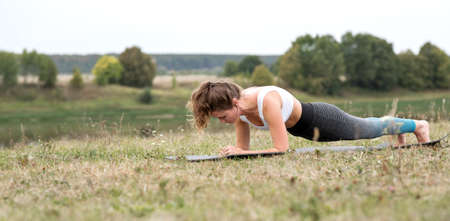 Young sporty woman doing fitness exercises near the river against the background of the forest. Young sporty woman doing fitness exercises near the river against the background of the forest.の写真素材