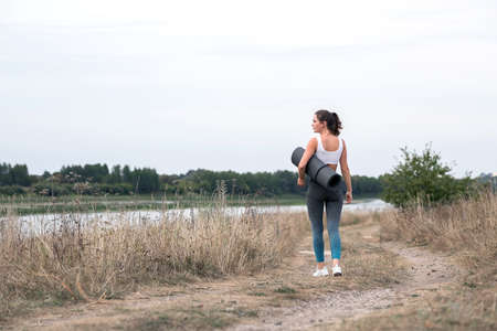 Young sporty woman doing fitness exercises near the river against the background of the forest. Young sporty woman doing fitness exercises near the river against the background of the forest.の写真素材
