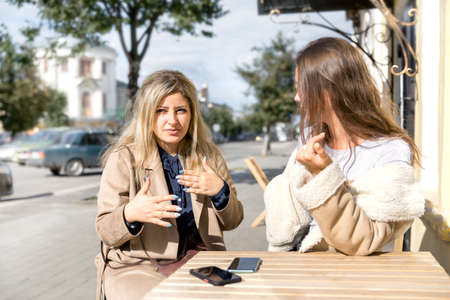 Two girls are sitting at a cafe table in a provincial city.の写真素材