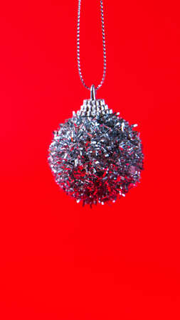 Subject of a Christmas decoration on a red solid background. New year's ball. Minimalism pattern. Copyspace. Vertical banner.の写真素材