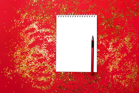 Notepad for notes on a festive red background with gold particles. Holiday design.の写真素材