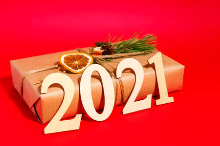 New year or Christmas banner on a red background.Gift in a box with decoration for the new year 2021. Beautiful box on a red background for a holiday. Creative gift wrapping with your own hands.の写真素材