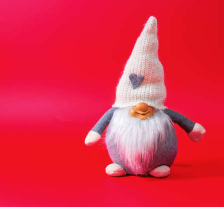 Festive scarf on a red background as a symbol of the new year. Old charming dwarf for happy new year and merry Christmas, Valentine's day, birthday.の写真素材