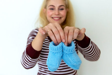 A pregnant woman holds in hands of blue socks for the baby.の写真素材