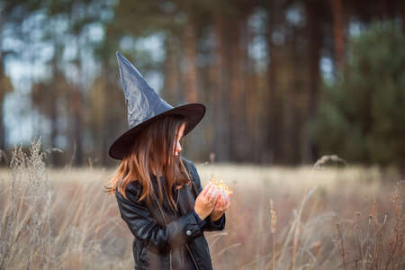 A cute girl in a Halloween costume is holding a medical face mask. Lay next to the orange pumpkins.の写真素材