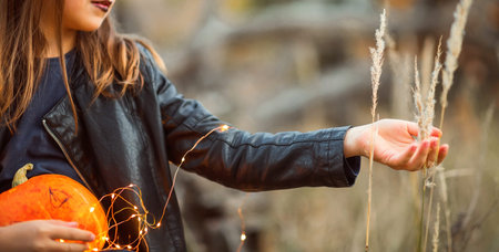 A cute girl in a Halloween costume is holding a medical face mask. Lay next to the orange pumpkins.の写真素材