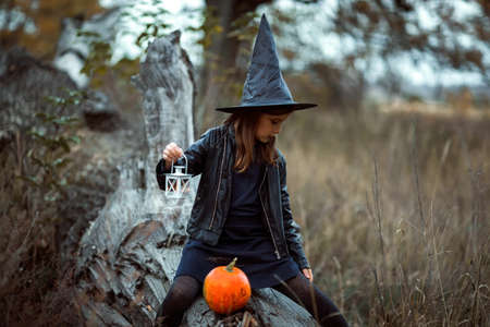 A cute girl in a Halloween costume is holding a medical face mask. Lay next to the orange pumpkins.の写真素材