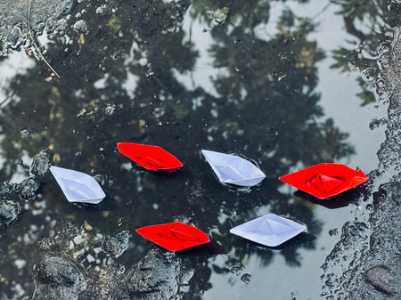 Paper boats floating in the puddle, closeup of photo.